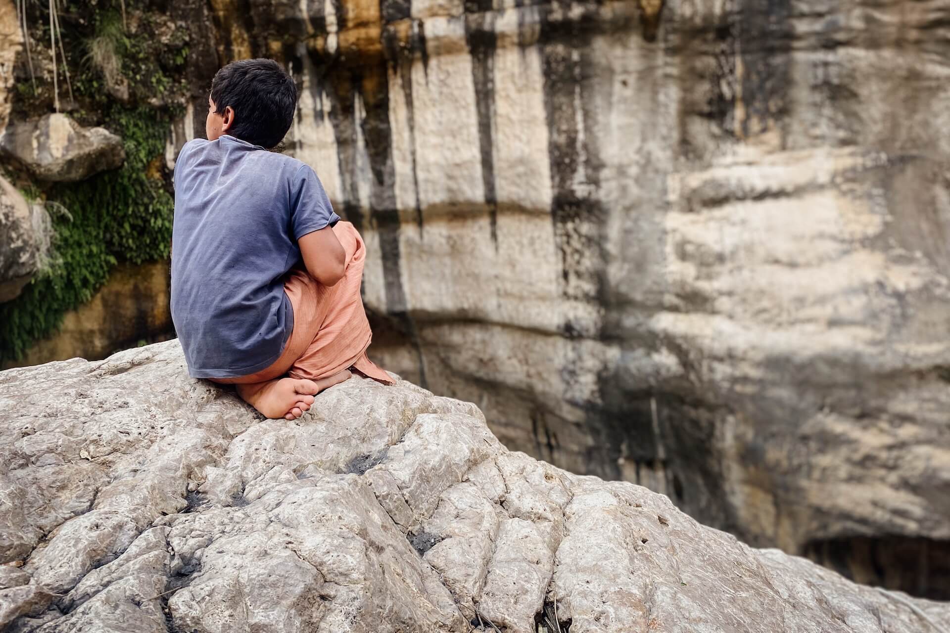 Een kleine jongen wijst de weg in Wadi Tiwi in Oman